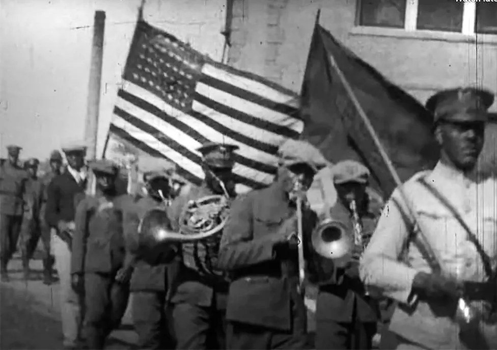 A Black marching band marching with the American flag.