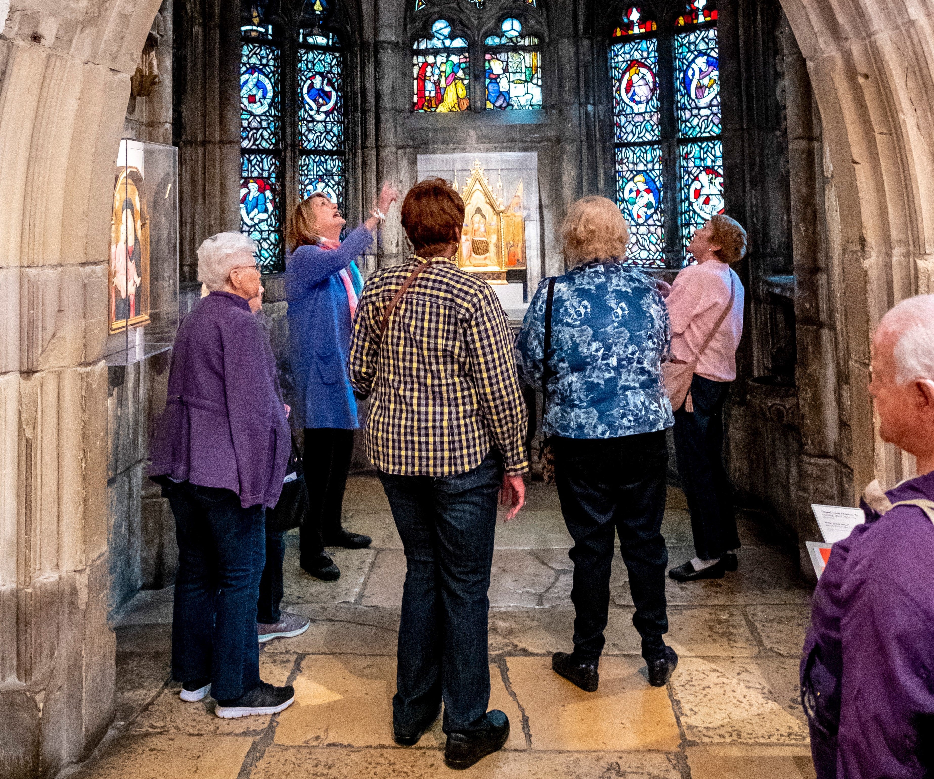Group of seniors on a tour, looking at stained glass. 
