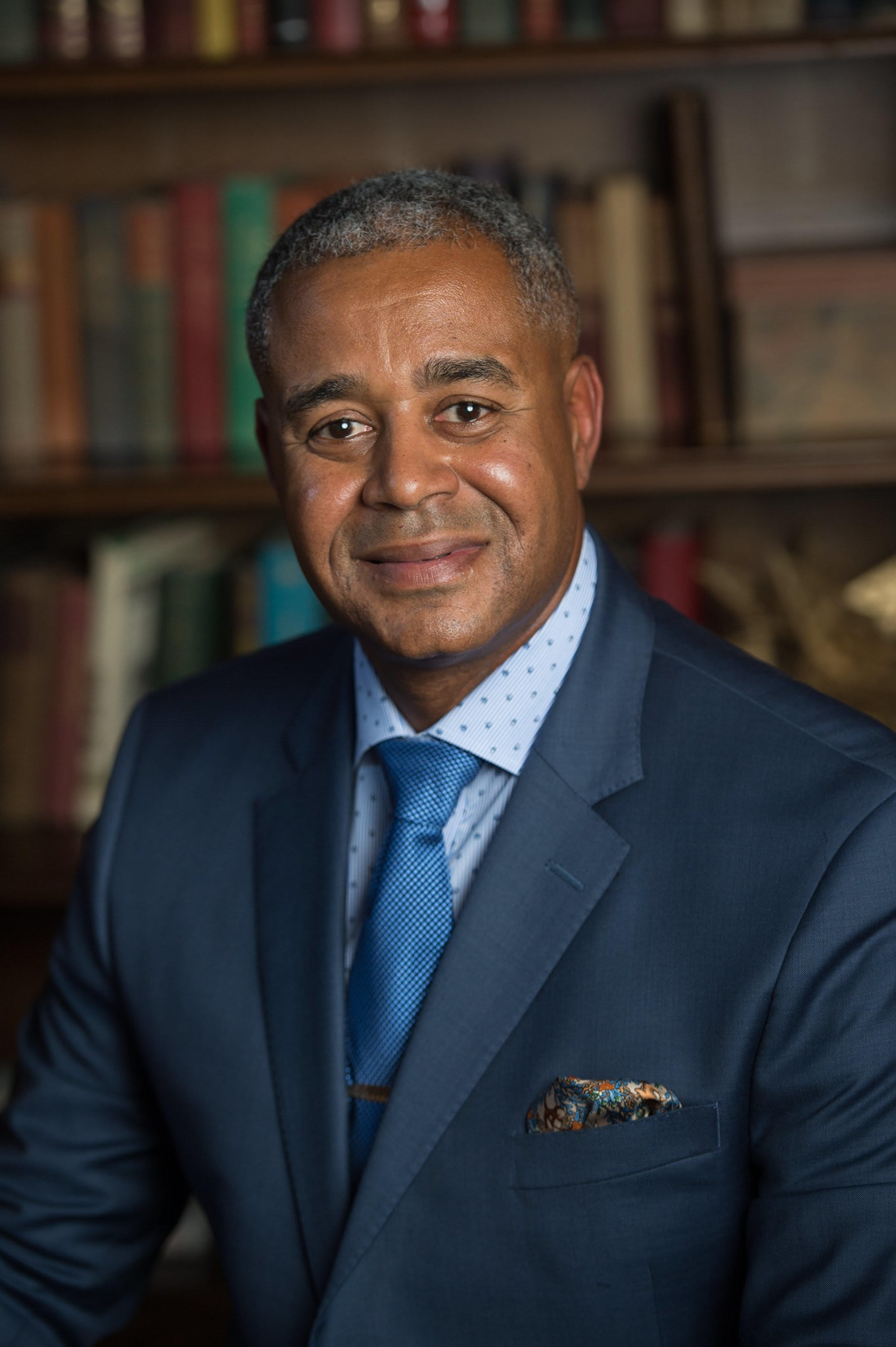 Lane Coleman, a Black man with graying hair wearing a blue suit and tie.