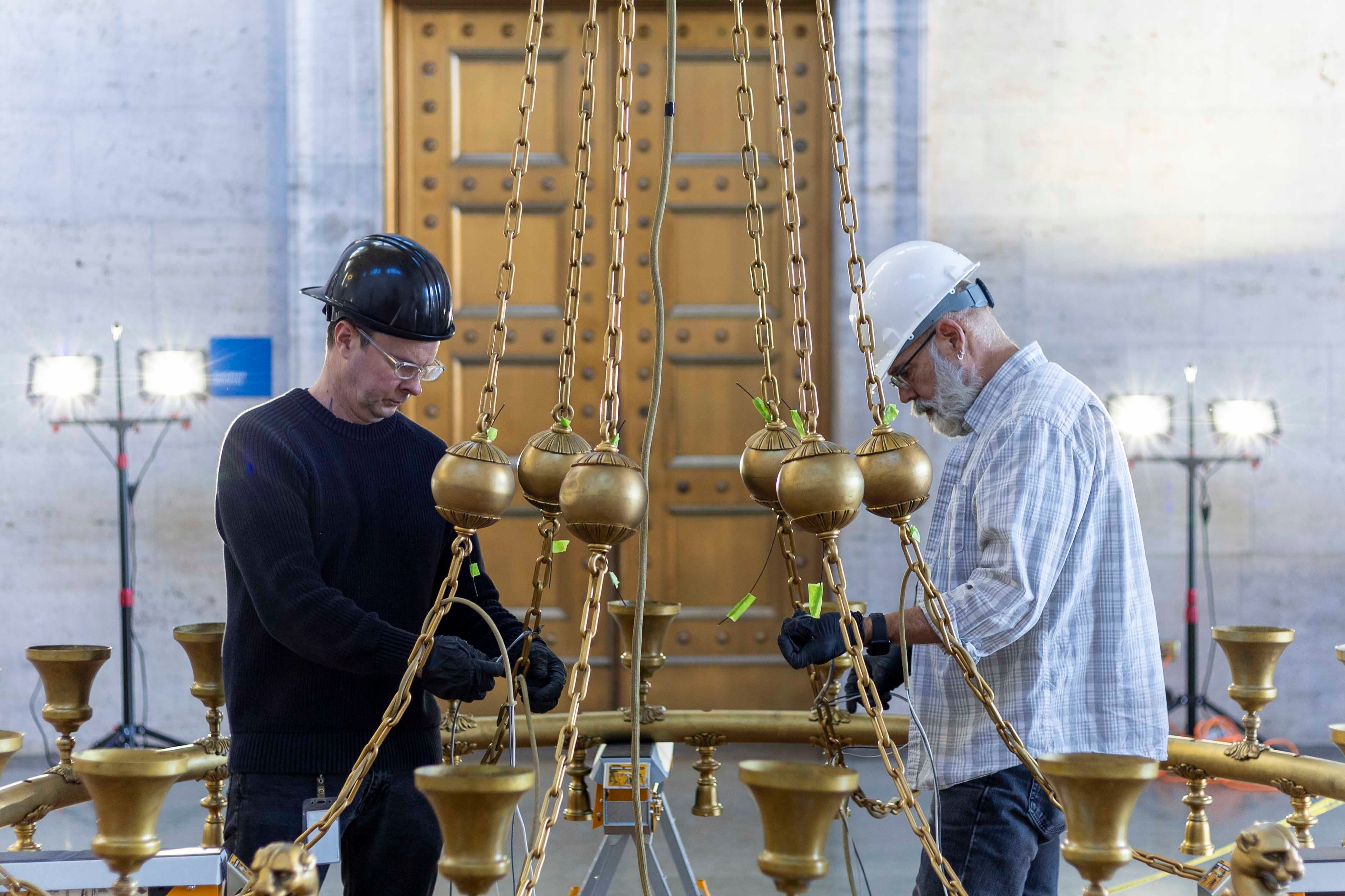 DIA Collections Management team members inspect the chandelier