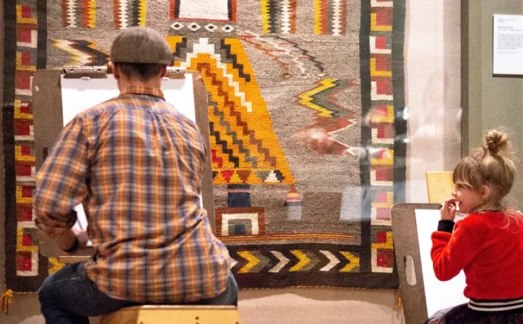 Young girl and father looking at Native American art