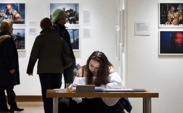 An educator sits at a table to write down notes during a photography exhibition