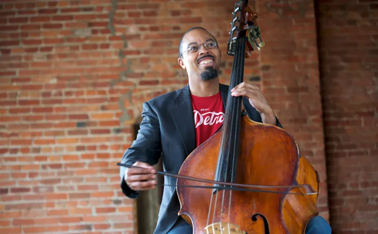 Bassist-composer Rick Robinson sitting and playing an upright bass with a bow