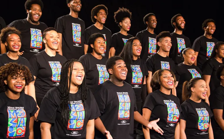 Mosaic youth choir lined up in rows on stage wearing matching black t-shirts with the Mosaic logo