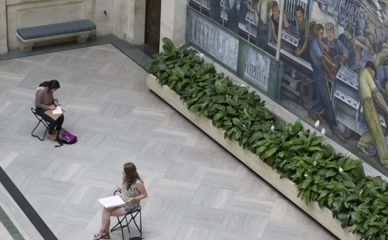 Patrons drawing while sitting on gallery stools in the DIA's Rivera Court