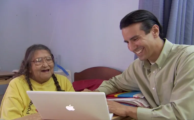Two people smiling and using a macbook