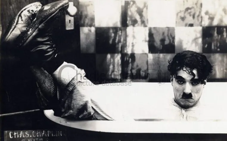 Charlie Chaplin pictured in a bathtub, fully clothed