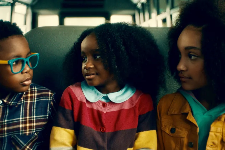 Three kids sit on a bus seat