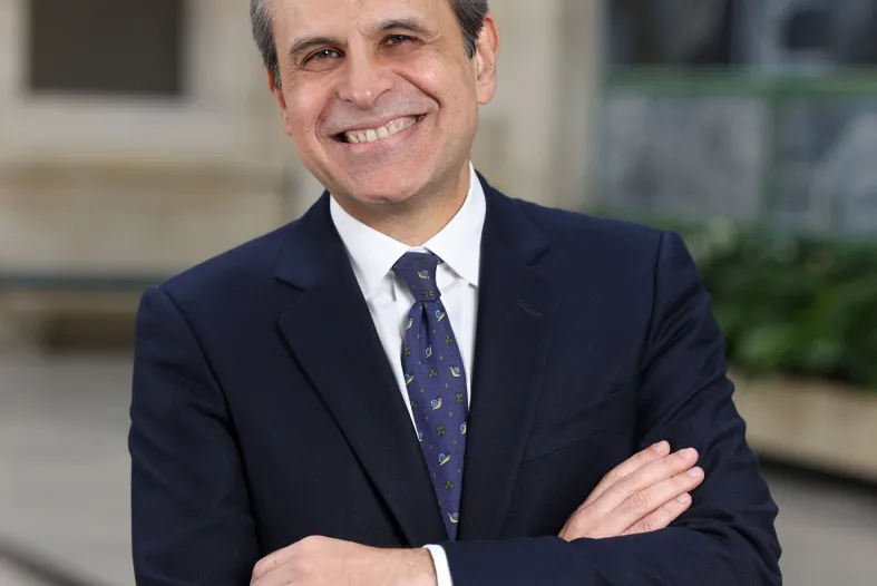 Salvador Salort Pons in a blue suit and tie, smiles with his arms folded in the DIA's Rivera Court.