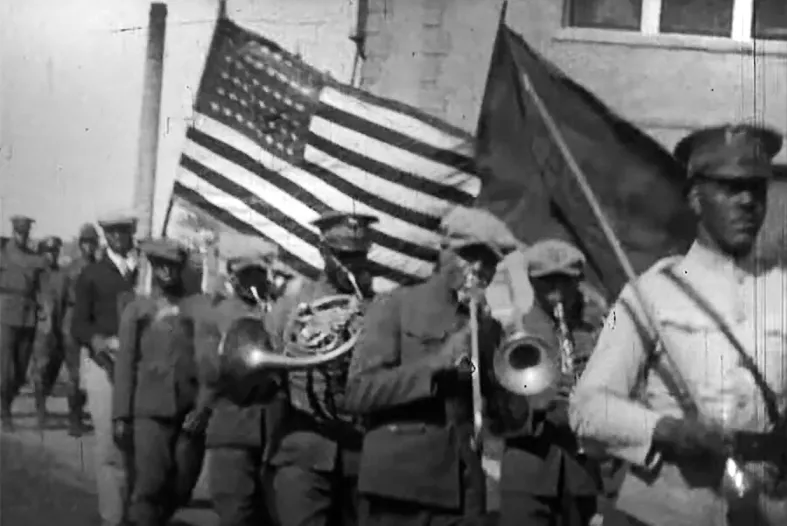 A Black marching band marching with the American flag.