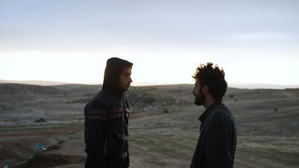 Two people face each other in a desert