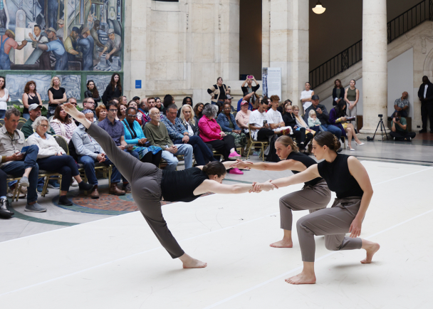 Dancers performing in Rivera Court, with spectators lined against the walls