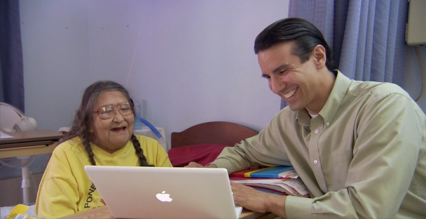 Two people smiling and using a macbook