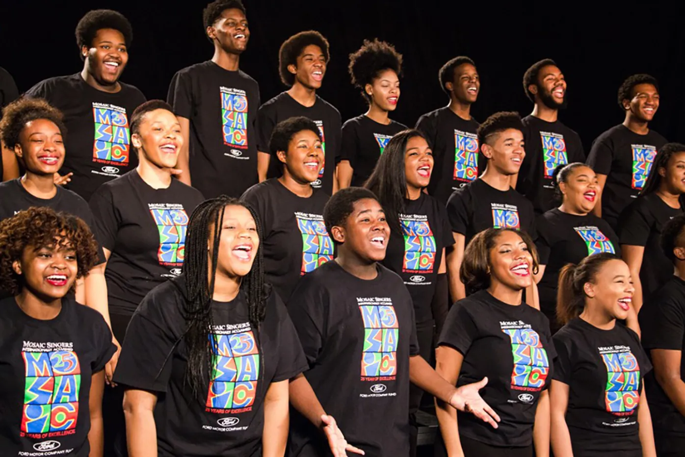 Mosaic youth choir lined up in rows on stage wearing matching black t-shirts with the Mosaic logo