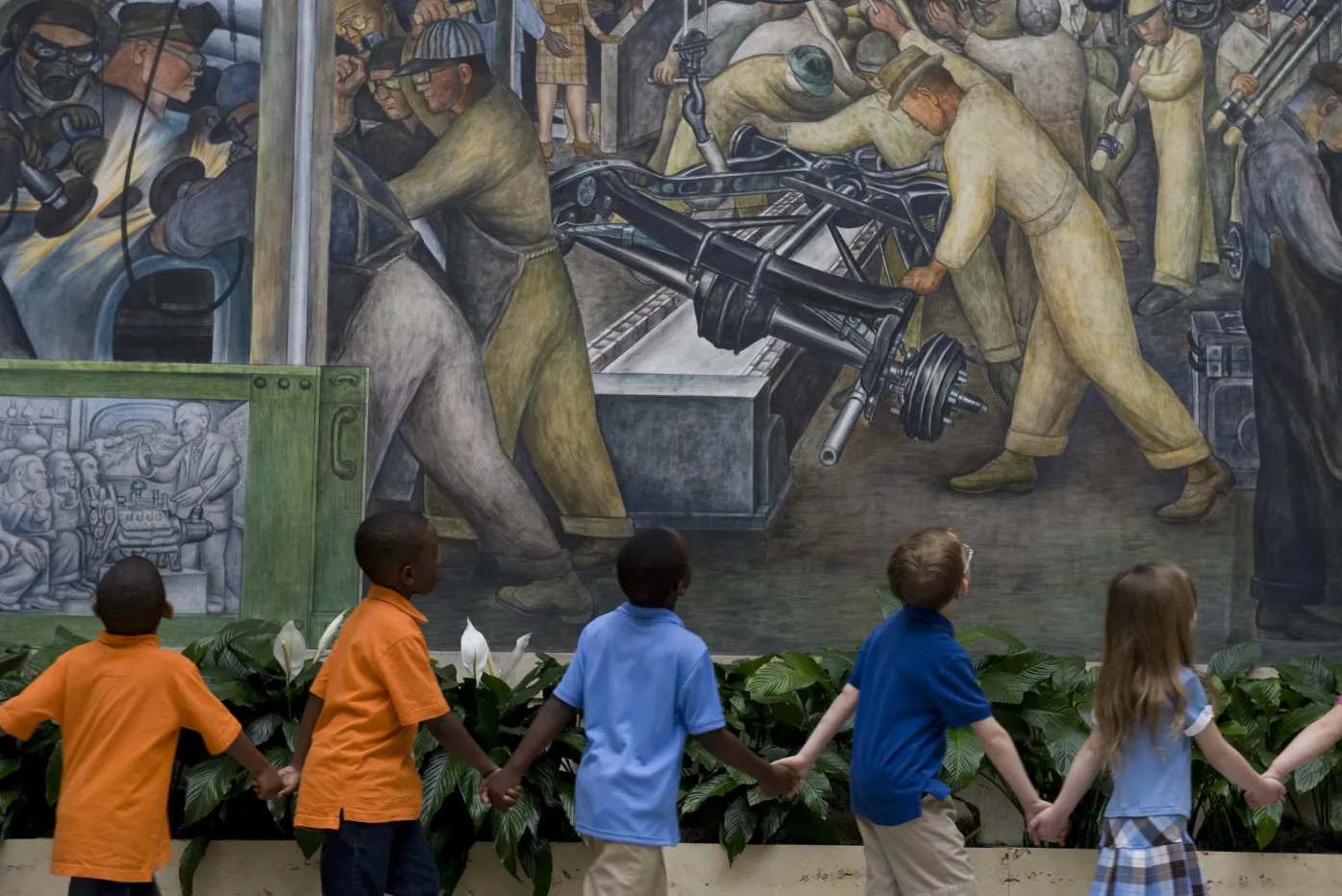 Kids holding hands and walking through the DIA&#039;s Rivera Court