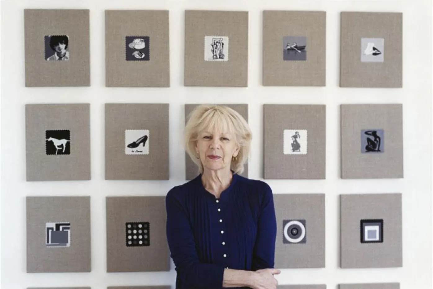 Artist Elaine Reichek standing in front of a wall of her artworks