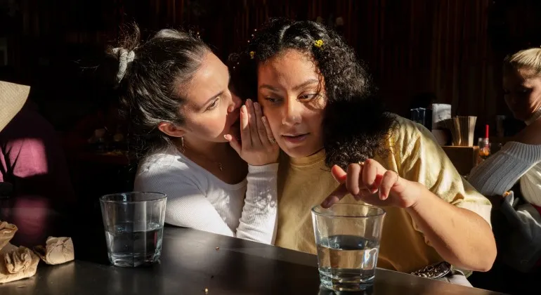 Young girl whispers to adult female