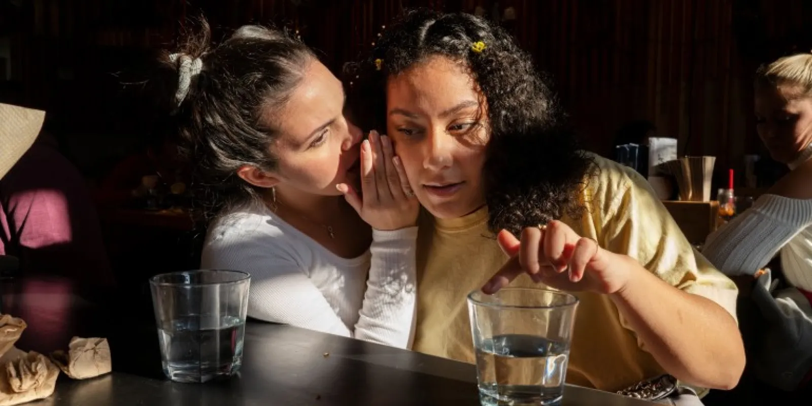 Young girl whispers to adult female
