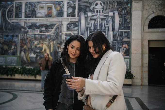 Two patrons using the digital guide on their phone in the DIA's Rivera Court