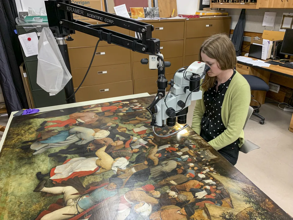 Conservator Blair Bailey uses a stereo microscope to examine the top section of The Wedding Dance.