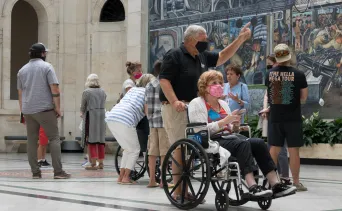 Man pushing woman in wheelchair in Rivera Court