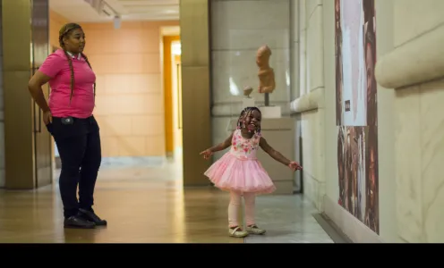 Small child in tutu points at artwork inside of the DIA