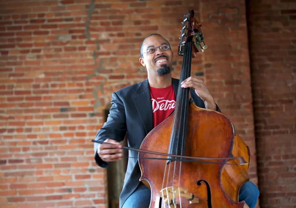 Bassist-composer Rick Robinson sitting and playing an upright bass with a bow