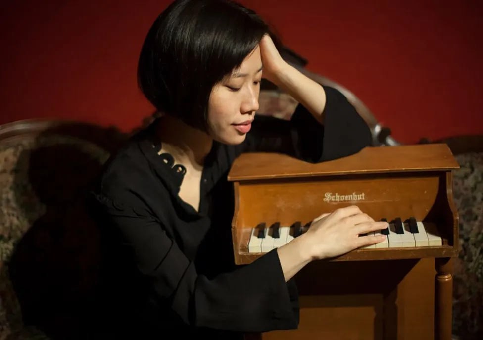 Phyllis Chen pictured with her arms around a tiny piano.