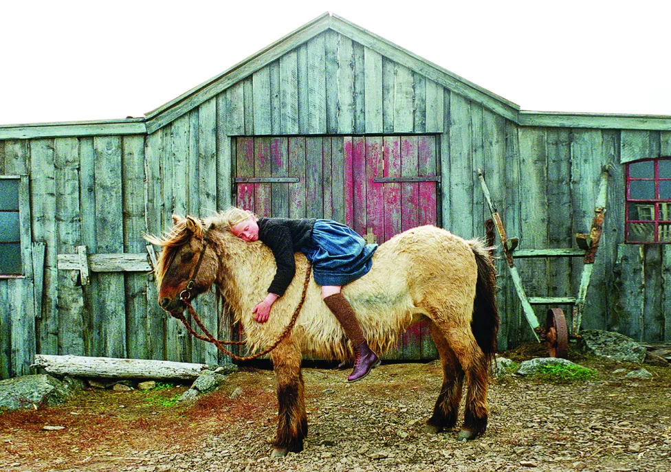 A girl lays on top of a pony, giving it a big hug.
