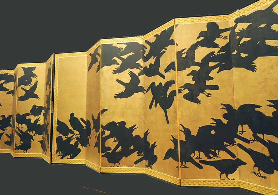 A long, unfolded yellow paper printed with swarms of black birds. 