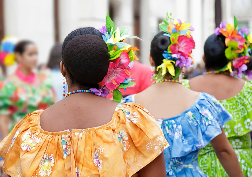 Caribbean dancers in colorful dresses, pictured from behind
