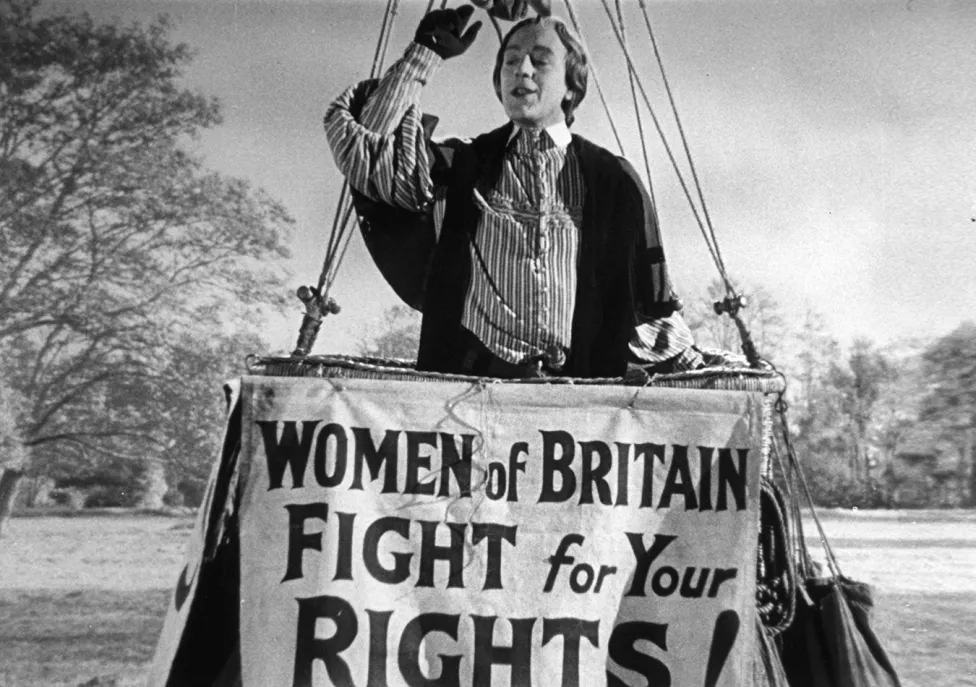 A person in a large basket behind the sign "Women of Britain Fight for your Rights"
