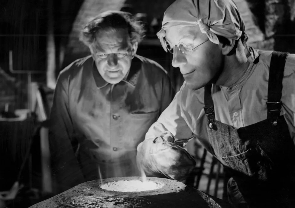 Two people hover over a smelting tool
