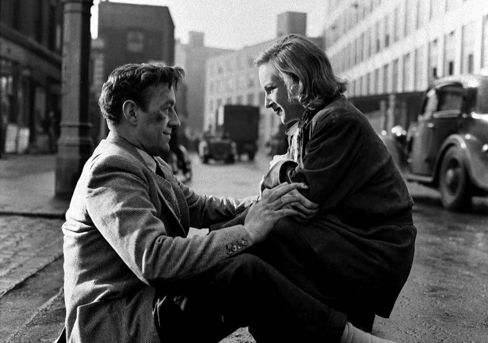Two people crouch in the street
