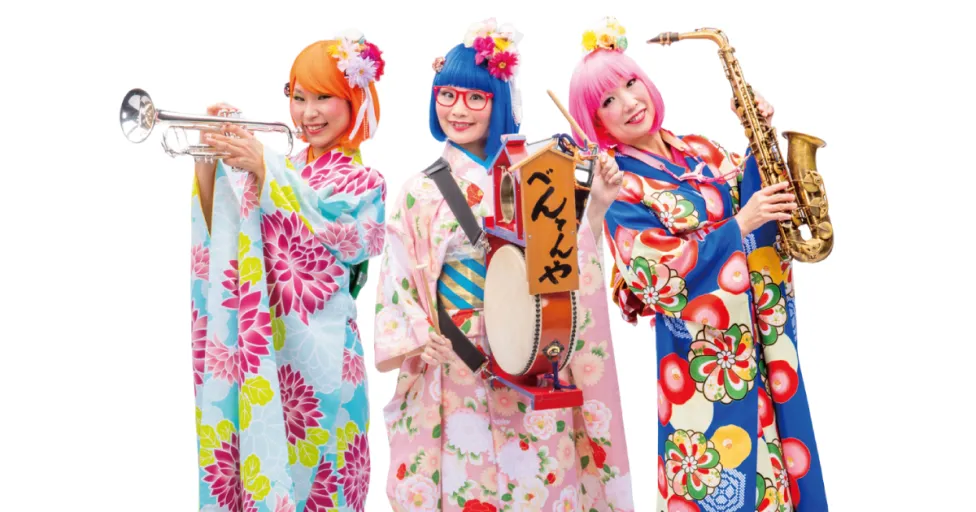 Three women holding instruments and wearing colorful kimonos