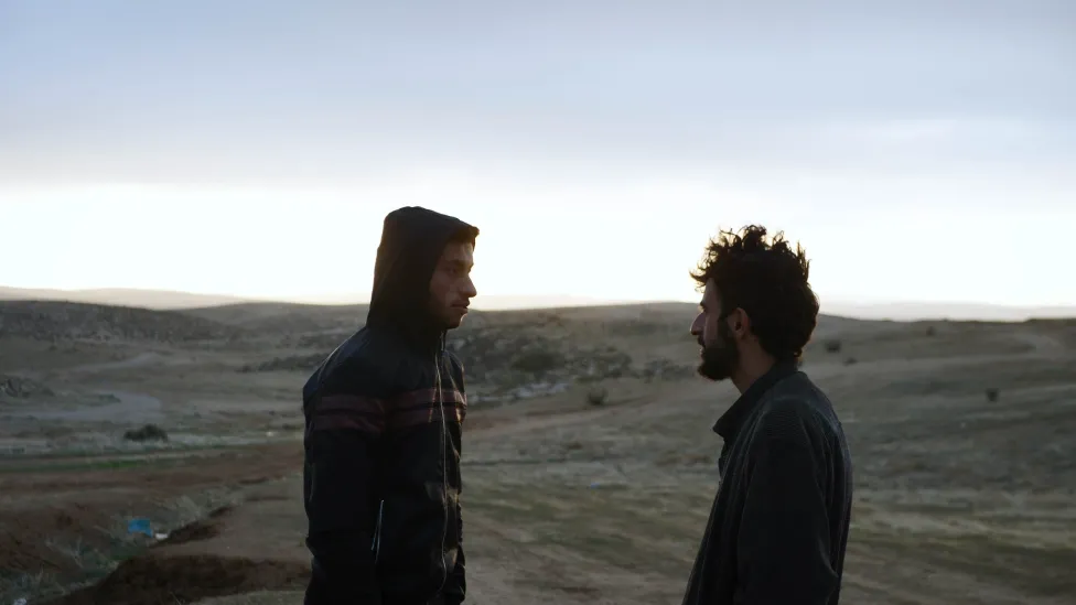 Two people face each other in a desert