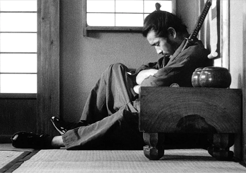 A man sits on the ground hugging a sword