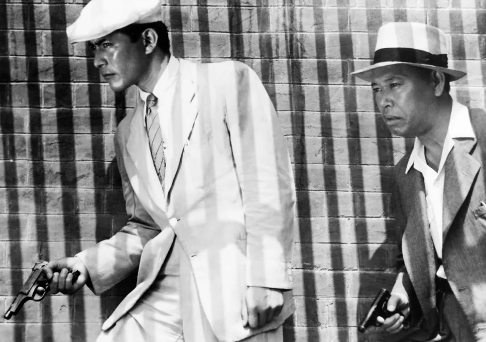 Two men with guns in suits and hats