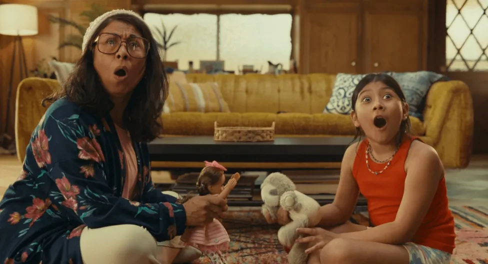 A mom and child sit on a living room floor in shock
