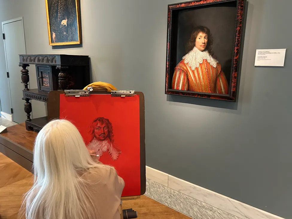 A patron working on a bright red canvas in the Fashionable Living galleries at the DIA