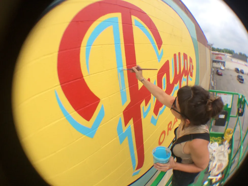 Kelly Golden, painting the Faygo logo on a wall