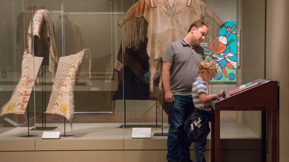 A man and a child read an interpretive plaque in the African Art galleries at the Detroit Institute of Arts.
