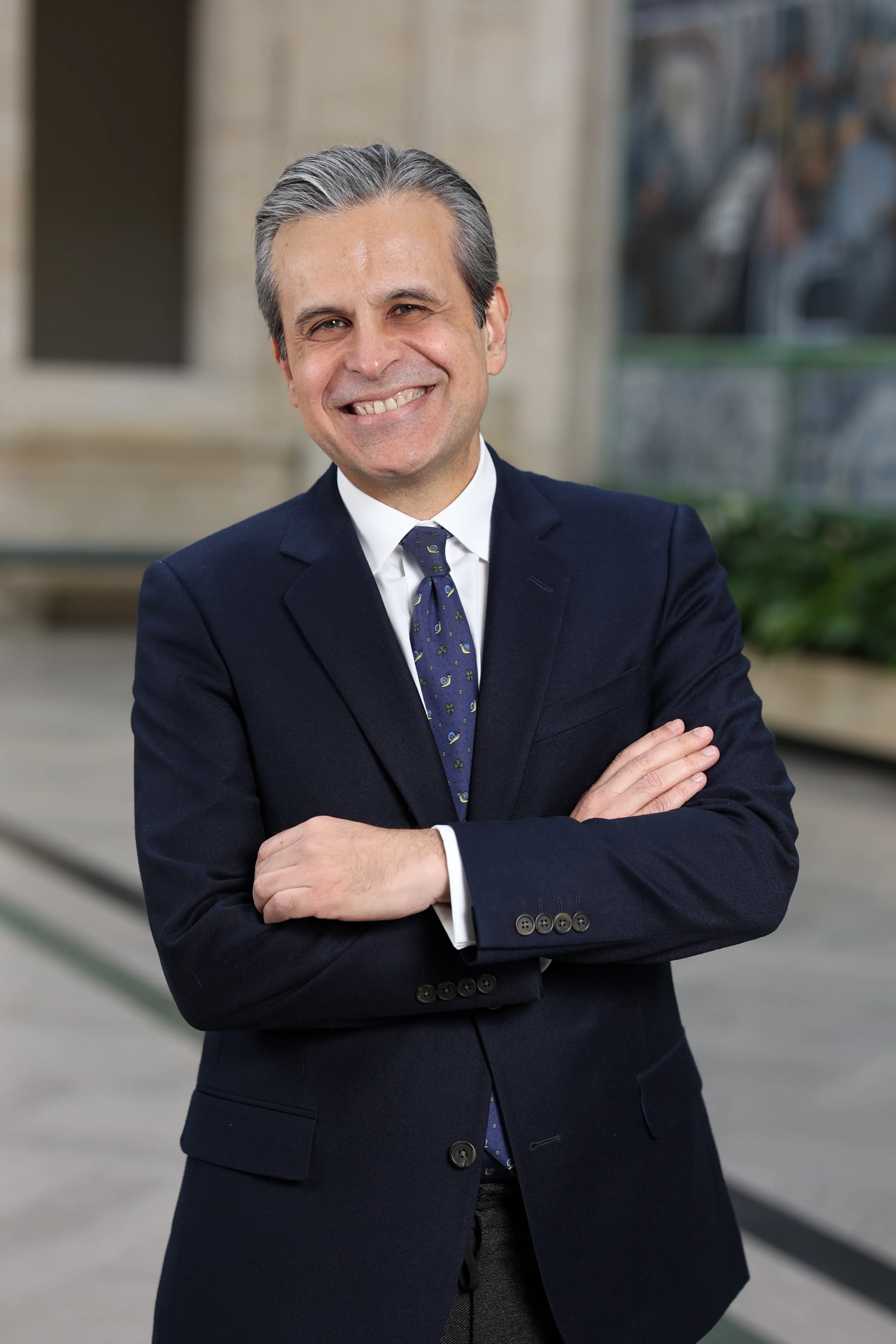 Salvador Salort Pons in a blue suit and tie, smiles with his arms folded in the DIA's Rivera Court.
