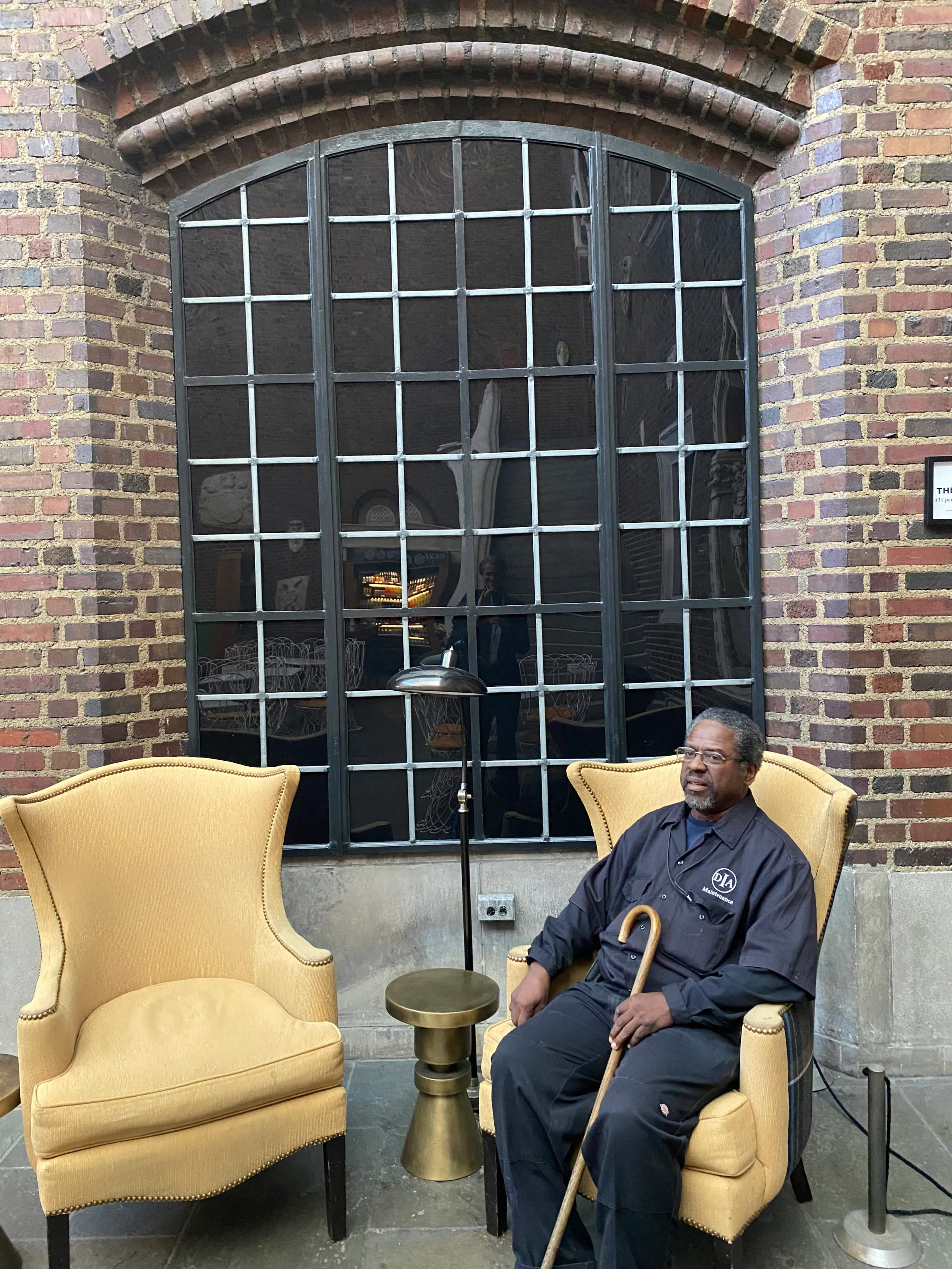 James Burts sits on a yellow winged-back chair in Kresge Court.
