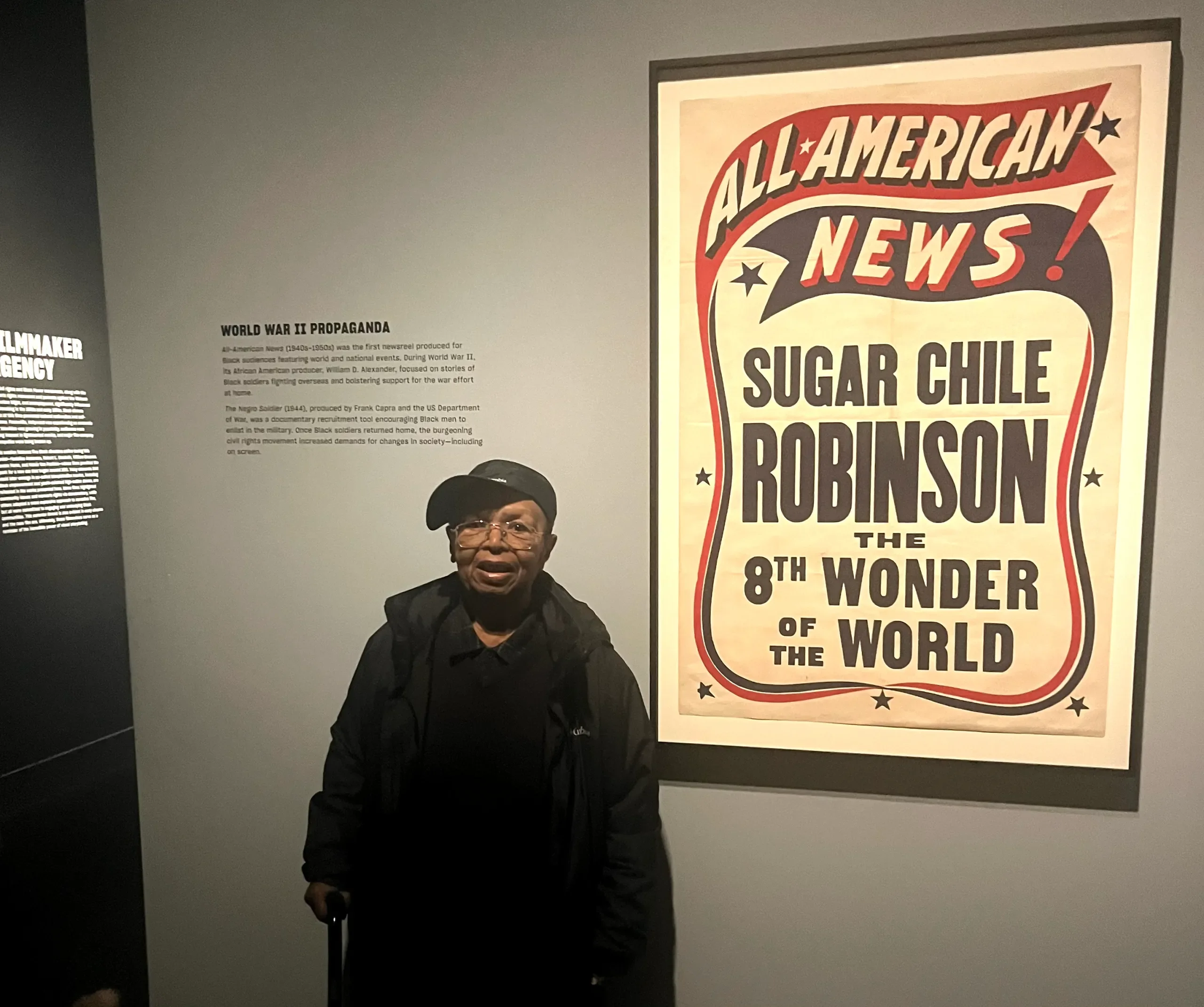 Sugar Chile Robinson of Detroit poses with a news poster of his name in the exhibition Regeneration: Black Cinema 1898 – 1971 at the Detroit Institute of Arts.