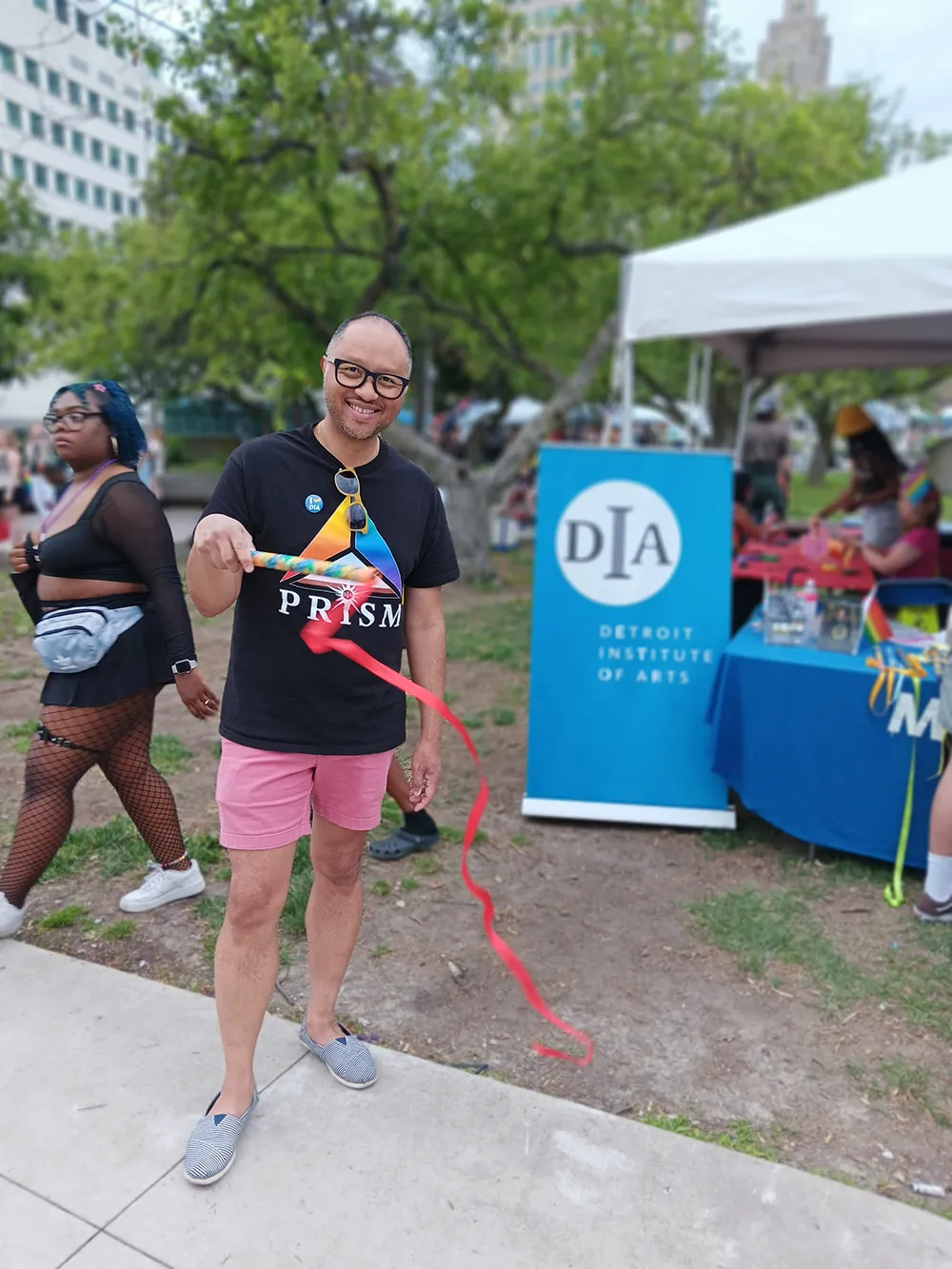 DIA team member Phil Rivera waves a rythmic ribbon baton in front of the artmaking tent at Motor City Pride
