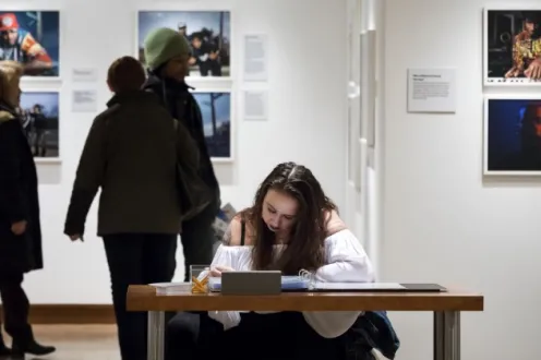 An educator sits at a table to write down notes during a photography exhibition