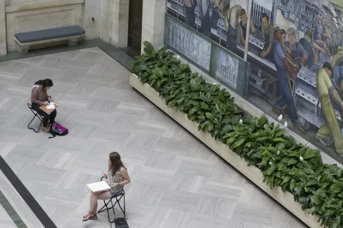 Patrons drawing while sitting on gallery stools in the DIA's Rivera Court
