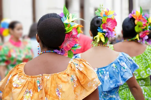 Caribbean dancers in colorful dresses, pictured from behind