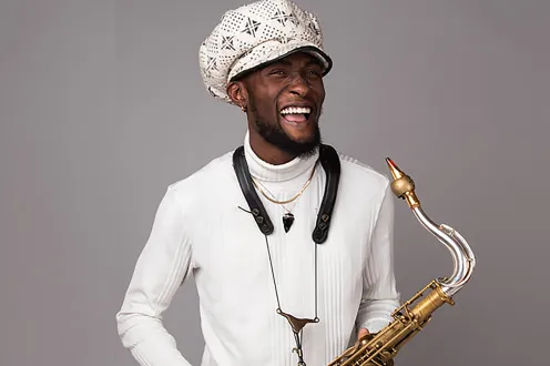 Isaiah Collier poses in a white hat and shirt with a saxophone 